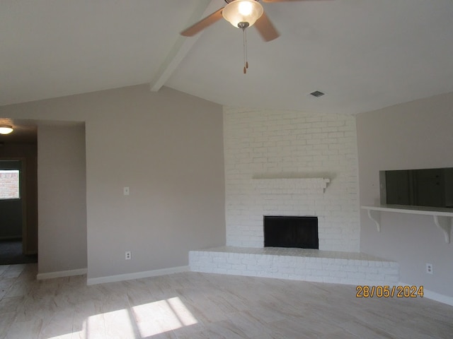 unfurnished living room featuring light wood-type flooring, vaulted ceiling with beams, a fireplace, and ceiling fan