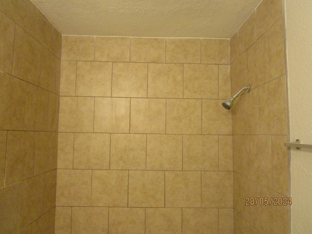 room details featuring a textured ceiling and tiled shower