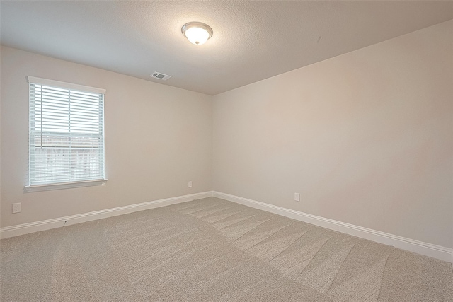 carpeted empty room featuring a textured ceiling