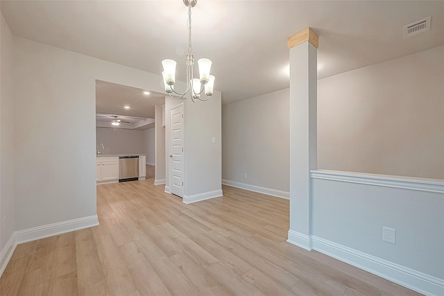 unfurnished dining area featuring ceiling fan with notable chandelier, light hardwood / wood-style floors, and ornate columns