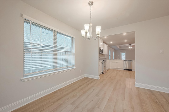 kitchen featuring light hardwood / wood-style flooring, white cabinets, hanging light fixtures, and appliances with stainless steel finishes