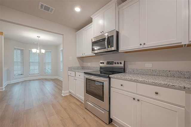 kitchen with white cabinets, stainless steel appliances, a notable chandelier, and light hardwood / wood-style floors