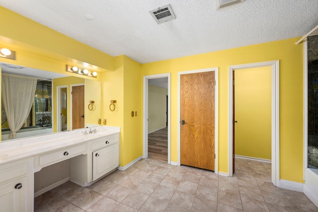 bathroom featuring vanity, a washtub, tile patterned floors, and a textured ceiling