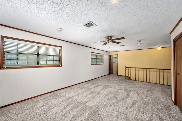 carpeted spare room featuring crown molding, ceiling fan, and a textured ceiling