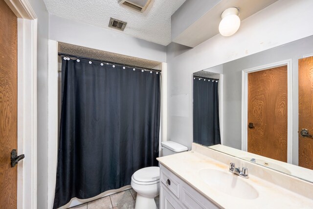 bathroom with tile patterned floors, toilet, a textured ceiling, and vanity