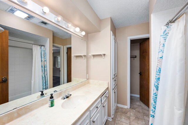 bathroom with vanity, tile patterned flooring, a textured ceiling, and walk in shower