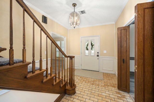 entryway featuring ornamental molding, a chandelier, and a textured ceiling