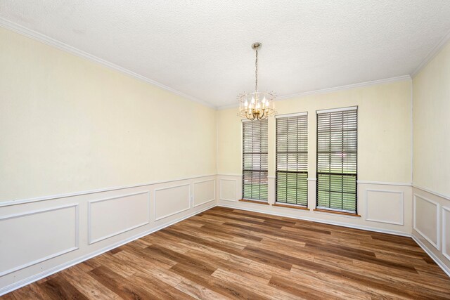 unfurnished dining area with ornamental molding, wood-type flooring, a chandelier, and a textured ceiling