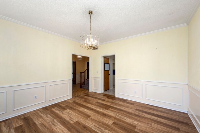 unfurnished room featuring ornamental molding, wood-type flooring, a textured ceiling, and a notable chandelier