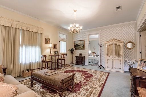 carpeted living room with a notable chandelier and crown molding