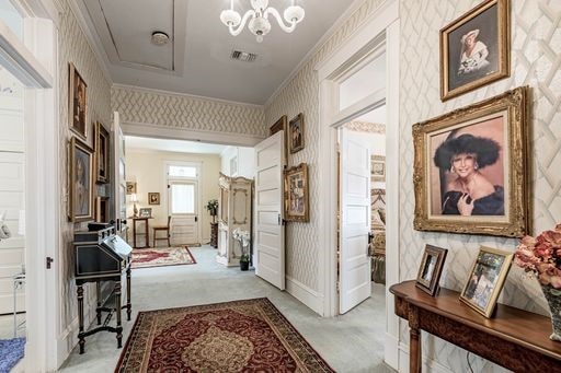 interior space featuring light carpet, crown molding, and a chandelier