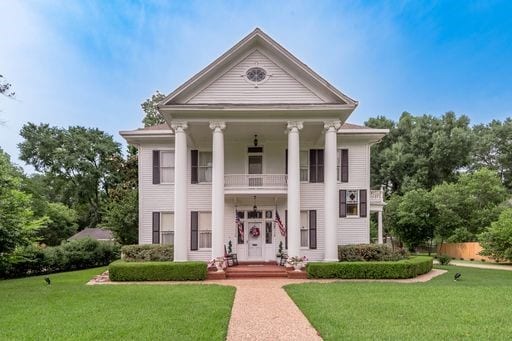 greek revival house with a front yard and a balcony