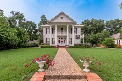 neoclassical / greek revival house featuring a front lawn and a balcony