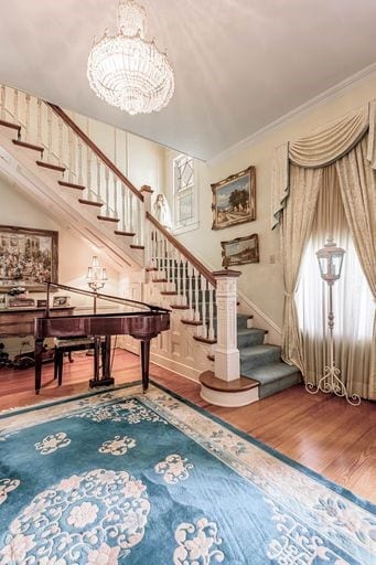 stairs featuring an inviting chandelier, hardwood / wood-style floors, and ornamental molding