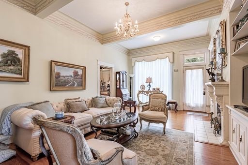 living room with a notable chandelier, ornamental molding, and hardwood / wood-style floors