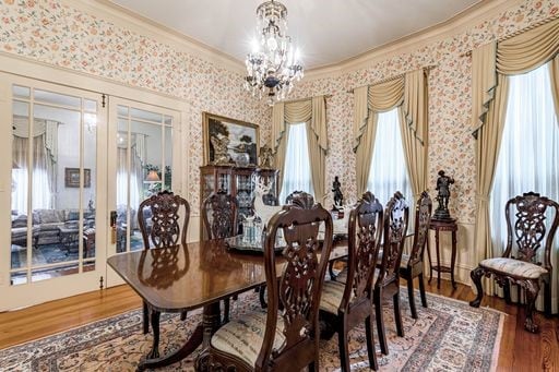 dining space featuring a healthy amount of sunlight, wood-type flooring, and an inviting chandelier