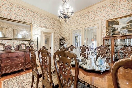 dining area with ornamental molding, wood-type flooring, and a chandelier