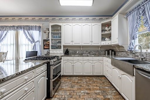 kitchen with stainless steel appliances, dark stone countertops, white cabinets, and sink