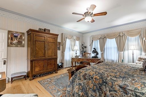 bedroom with light hardwood / wood-style floors, ceiling fan, and multiple windows