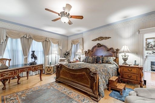 bedroom featuring ceiling fan, hardwood / wood-style flooring, crown molding, and multiple windows