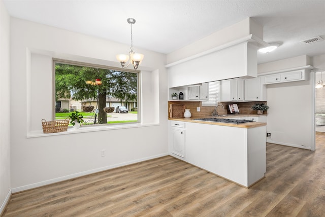 kitchen featuring white cabinets, pendant lighting, decorative backsplash, hardwood / wood-style flooring, and a notable chandelier