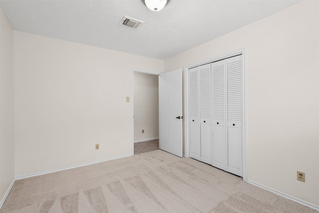 unfurnished bedroom featuring light carpet and a closet