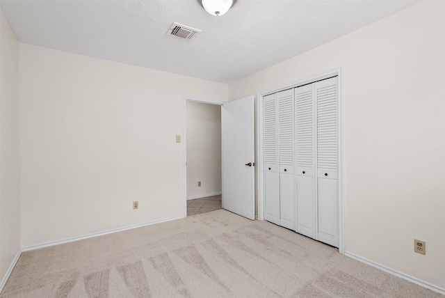 unfurnished bedroom featuring light colored carpet and a closet