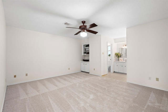 unfurnished living room with ceiling fan, light colored carpet, and a textured ceiling