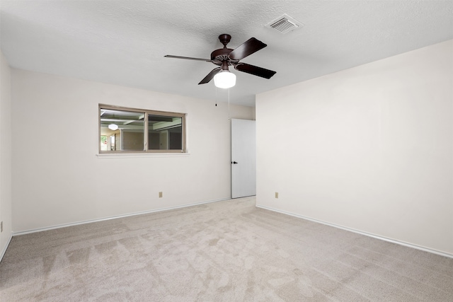 unfurnished room with light colored carpet, a textured ceiling, and ceiling fan