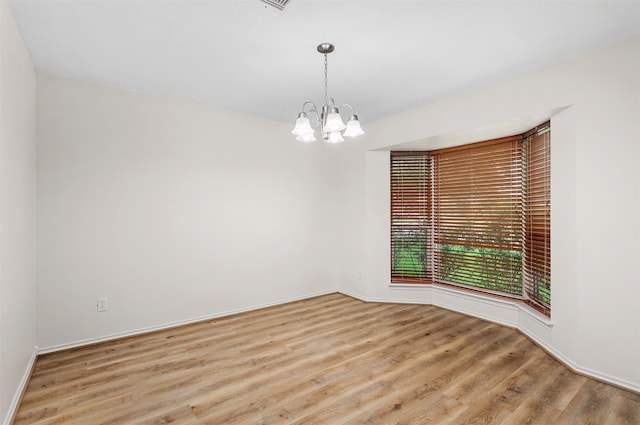 empty room with light hardwood / wood-style floors and a notable chandelier