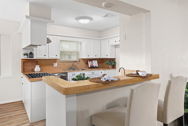 kitchen featuring white cabinetry, tasteful backsplash, sink, light hardwood / wood-style floors, and kitchen peninsula