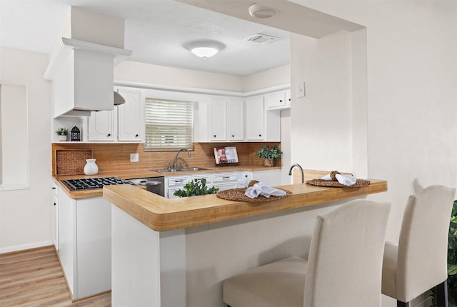 kitchen with sink, light hardwood / wood-style flooring, backsplash, white cabinets, and kitchen peninsula