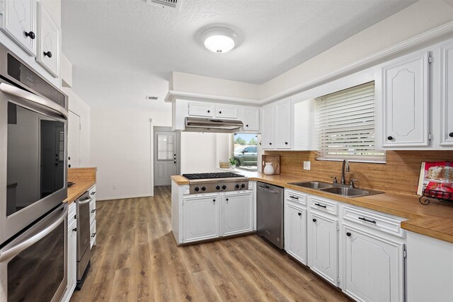 kitchen featuring sink, hardwood / wood-style flooring, stainless steel appliances, and white cabinetry