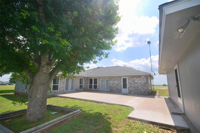 rear view of house featuring a lawn and a patio area