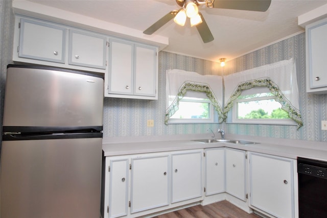 kitchen with light countertops, a sink, freestanding refrigerator, black dishwasher, and wallpapered walls