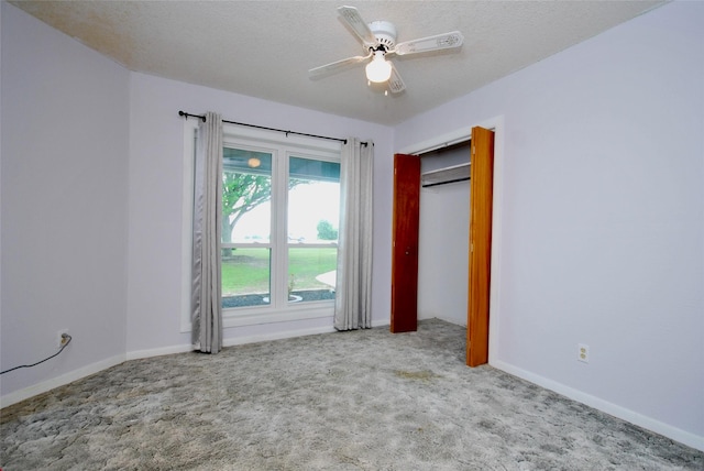 unfurnished bedroom featuring carpet floors, baseboards, a textured ceiling, and ceiling fan