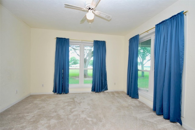 carpeted spare room featuring baseboards and ceiling fan