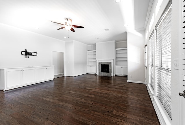 unfurnished living room featuring ceiling fan, dark hardwood / wood-style flooring, crown molding, and built in shelves