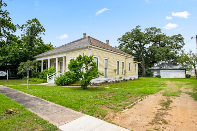 view of side of property with a porch, a garage, an outdoor structure, and a lawn