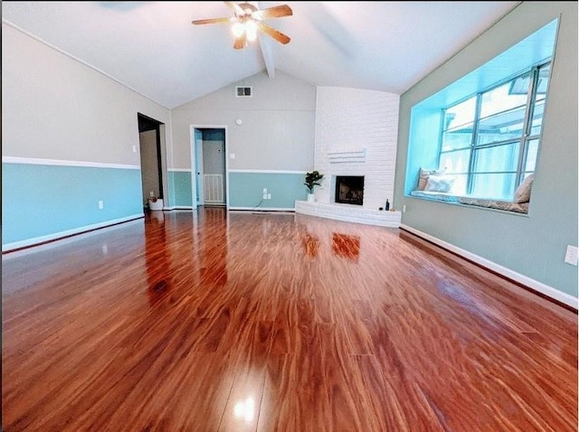 unfurnished living room featuring brick wall, a fireplace, ceiling fan, vaulted ceiling with beams, and dark wood-type flooring