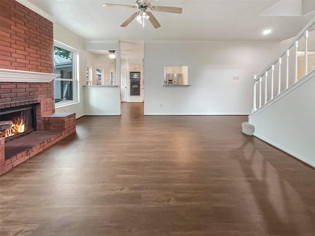 unfurnished living room with dark hardwood / wood-style floors, ceiling fan, ornamental molding, and a brick fireplace