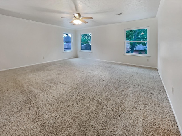 empty room featuring a textured ceiling, ceiling fan, carpet floors, and crown molding