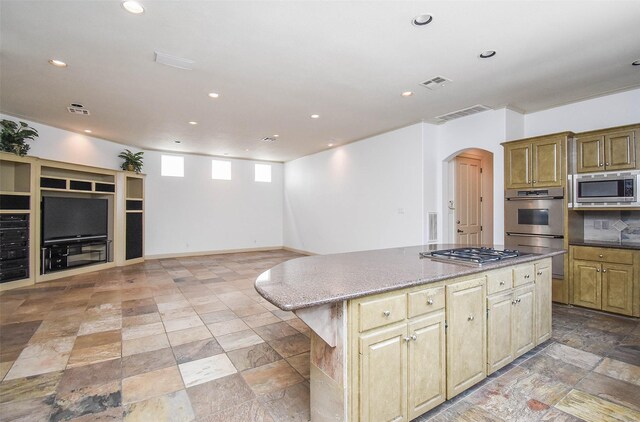 kitchen featuring appliances with stainless steel finishes, dark stone counters, light tile patterned floors, and a center island