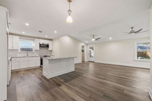 kitchen with decorative light fixtures, a center island, appliances with stainless steel finishes, dark hardwood / wood-style flooring, and white cabinets