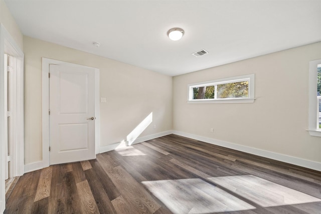 unfurnished room featuring a healthy amount of sunlight and dark wood-type flooring