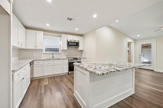 kitchen with stainless steel appliances, a kitchen island, sink, and white cabinets