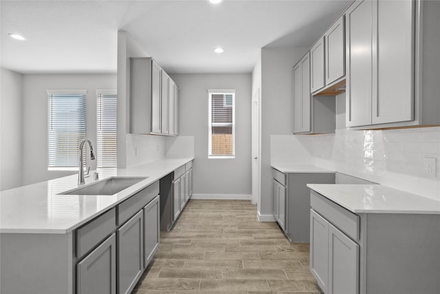 kitchen featuring backsplash, gray cabinetry, sink, light hardwood / wood-style flooring, and dishwasher