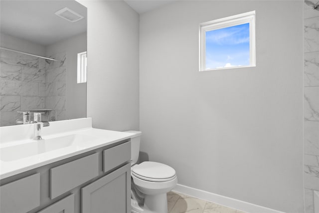 bathroom with a tile shower, vanity, and toilet