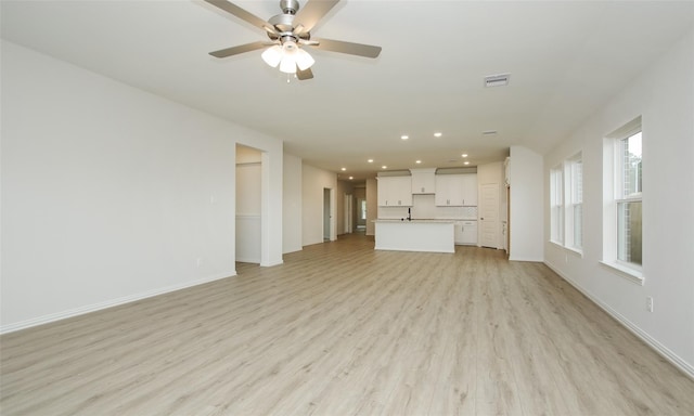 unfurnished living room featuring ceiling fan, sink, and light hardwood / wood-style flooring