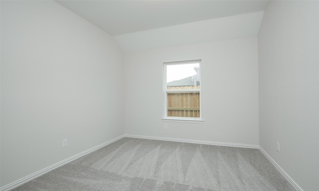 carpeted empty room with vaulted ceiling